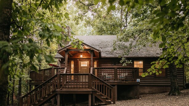 Une cabane rustique dotée d’une terrasse en bois, d’un escalier et d’un porche.
