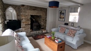 A living room with a stone fireplace, white sofas, a wooden coffee table, and a television. - Bijoux Cottage in Porthleven  5 mins walk  Beach/Harbour. Sleeps 2. Dog Friendly (Porthleven)