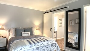 A bedroom with a bed, bedside lamps, a mirror, and a wardrobe.