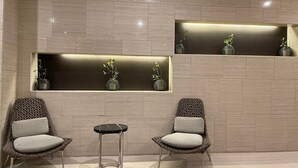 A modern interior with two wicker chairs, a small round table, and wall-mounted planters with greenery.