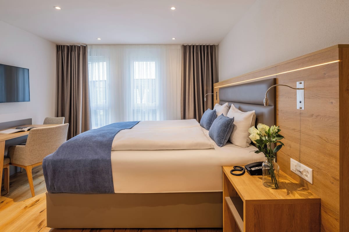 Een moderne hotelkamer met een groot bed, een bureau en een televisie.