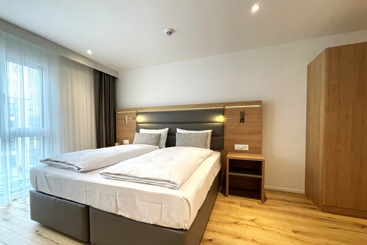Une chambre d’hôtel moderne, dotée d’un grand lit, de tables de chevet et d’une armoire.