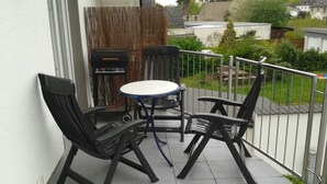 A small outdoor patio with a round table and two chairs, a grill, and a view of the surrounding neighborhood. - Pension Yildirim - quiet and central vacation apartment (1) (Leverkusen)