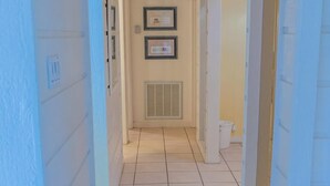 A narrow hallway with white walls and a tiled floor, leading to a door at the end. - Caribbean Vibes House 3 Bedroom Home by RedAwning (South Padre Island)