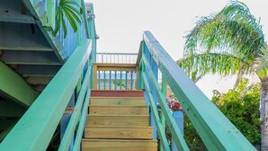 A wooden staircase with teal railings leading to a balcony. - Caribbean Vibes House 3 Bedroom Home by RedAwning (South Padre Island)