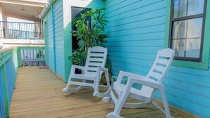 A porch with two rocking chairs and a wooden deck. - Caribbean Vibes House 3 Bedroom Home by RedAwning (South Padre Island)
