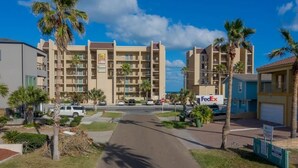 A multi-story hotel with a central courtyard, palm trees, and a FedEx sign. - Caribbean Vibes House 3 Bedroom Home by RedAwning (South Padre Island)