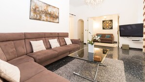 Ein modernes Wohnzimmer mit einem braunen Ecksofa, einem Glastisch und einem flachbildfernseher an der Wand.