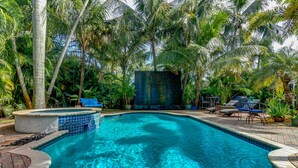 A swimming pool surrounded by palm trees and lounge chairs.