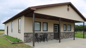 A single-story building with a covered patio area, stone accents around the lower windows, and a door with a window above it.