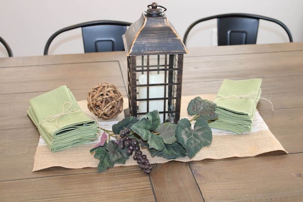 A wooden table with a lantern, green cloths, and grape decorations. - Prairieview Cottage Retreat - Hot Tub Sunsets (Sullivan)