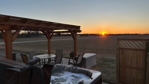 Un espace patio aménagé avec un jacuzzi, du mobilier d’extérieur et une vue sur le coucher de soleil.