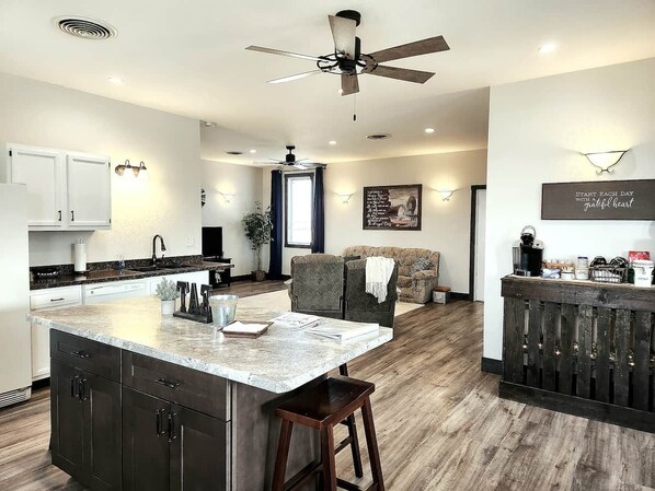 Cocina moderna con una isla central, armarios oscuros y ventilador de techo.