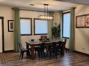 Un comedor con una mesa de madera, sillas negras, una lámpara colgante y una planta en maceta.