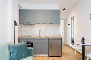 Uma cozinha moderna com armários cinza, painel de parede de mármore e lava-louças embutida.