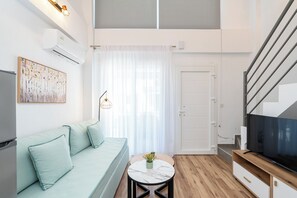 Uma sala de estar moderna com um sofá, uma TV, uma mesa pequena com um vaso e uma escada.