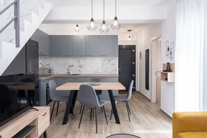 A modern kitchen with a marble backsplash, grey cabinets, and a wooden dining table with chairs. - Danai Residential Complex (Pangaio)
