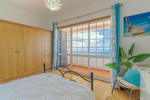 A bedroom with a large window, wooden wardrobe, and a bed with a white duvet. - Villa Black Rock (Vinhais)