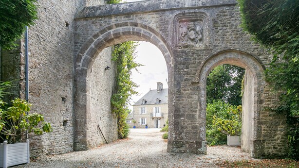 A stone archway leading to a building with a traditional facade.