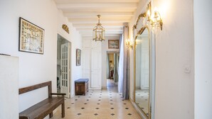 A hallway with a wooden bench, a map on the wall, and a large mirror.