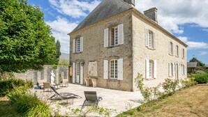 A stone house with a tiled patio, outdoor seating, and a garden.