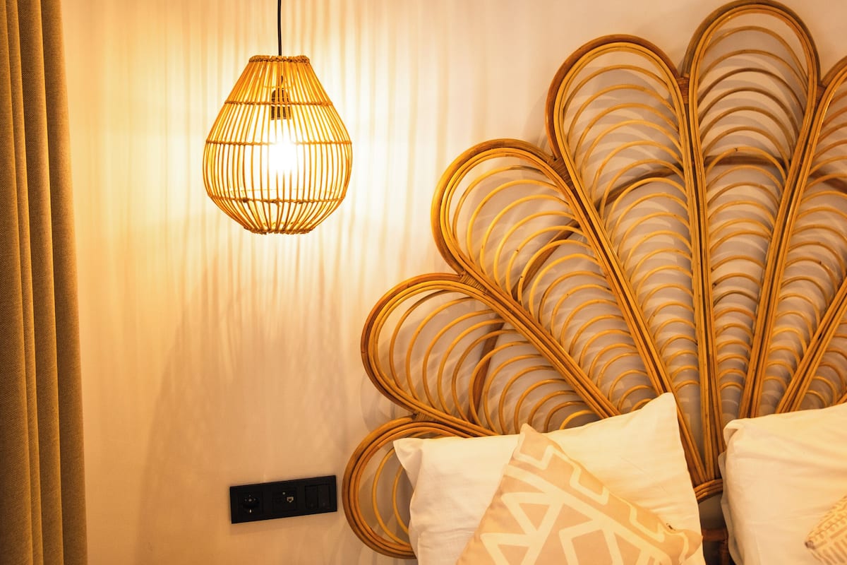 A room with a bed, a small round table, a wall-mounted light fixture, and a curtain.