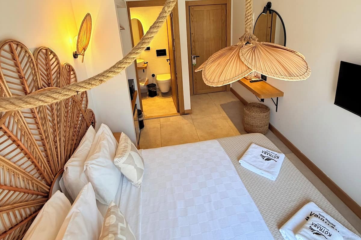 A bedroom with a bed, pillows, a hanging chair, a bedside table, and a wall-mounted TV.