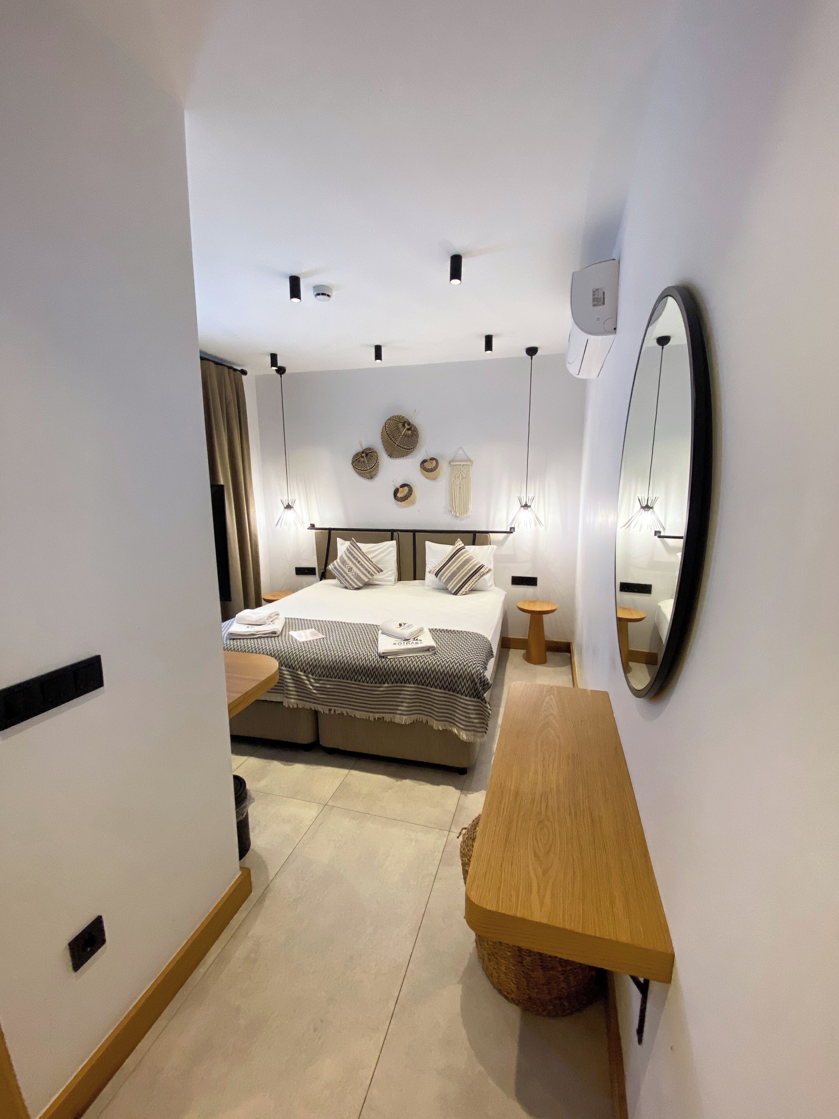 Un dormitorio moderno con cama, mesitas de noche, espejo e iluminación en la pared.