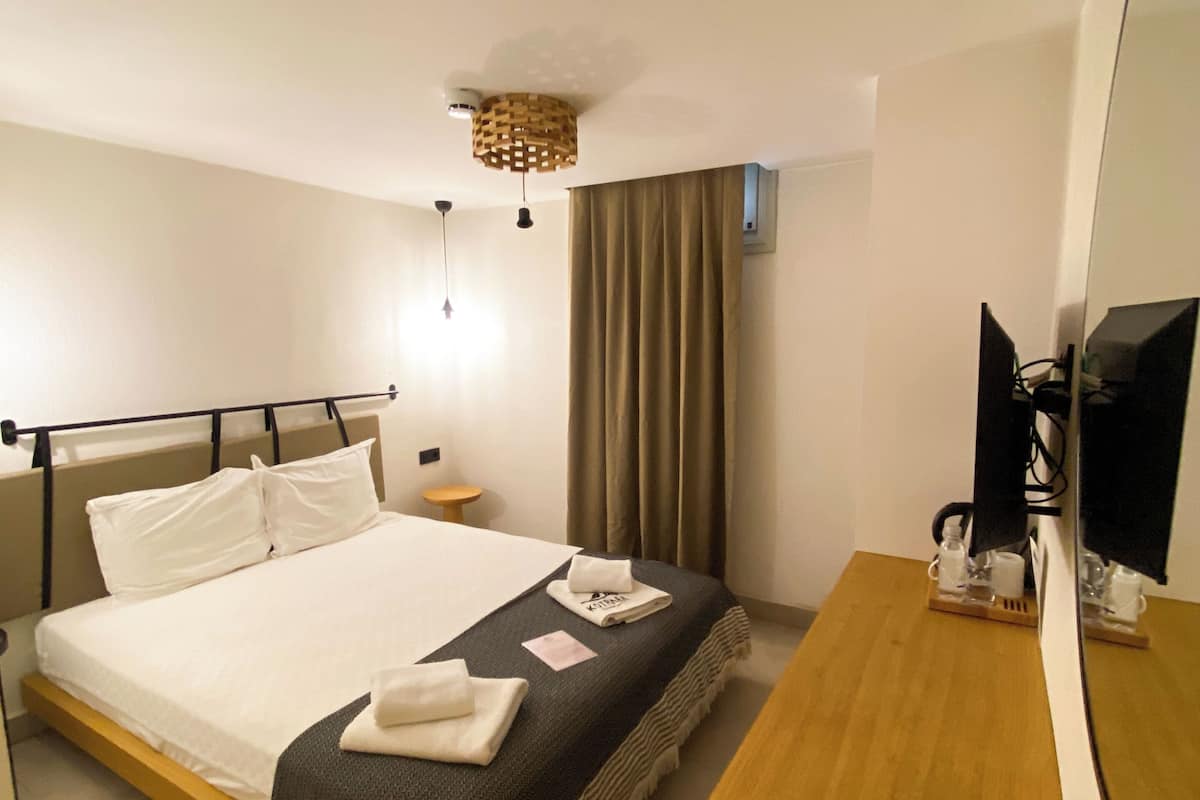 A hotel room with a bed, bedside table, TV, and a mirror.