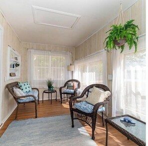 Relax in this spacious room with a high ceiling, large window, and comfortable wicker chairs.