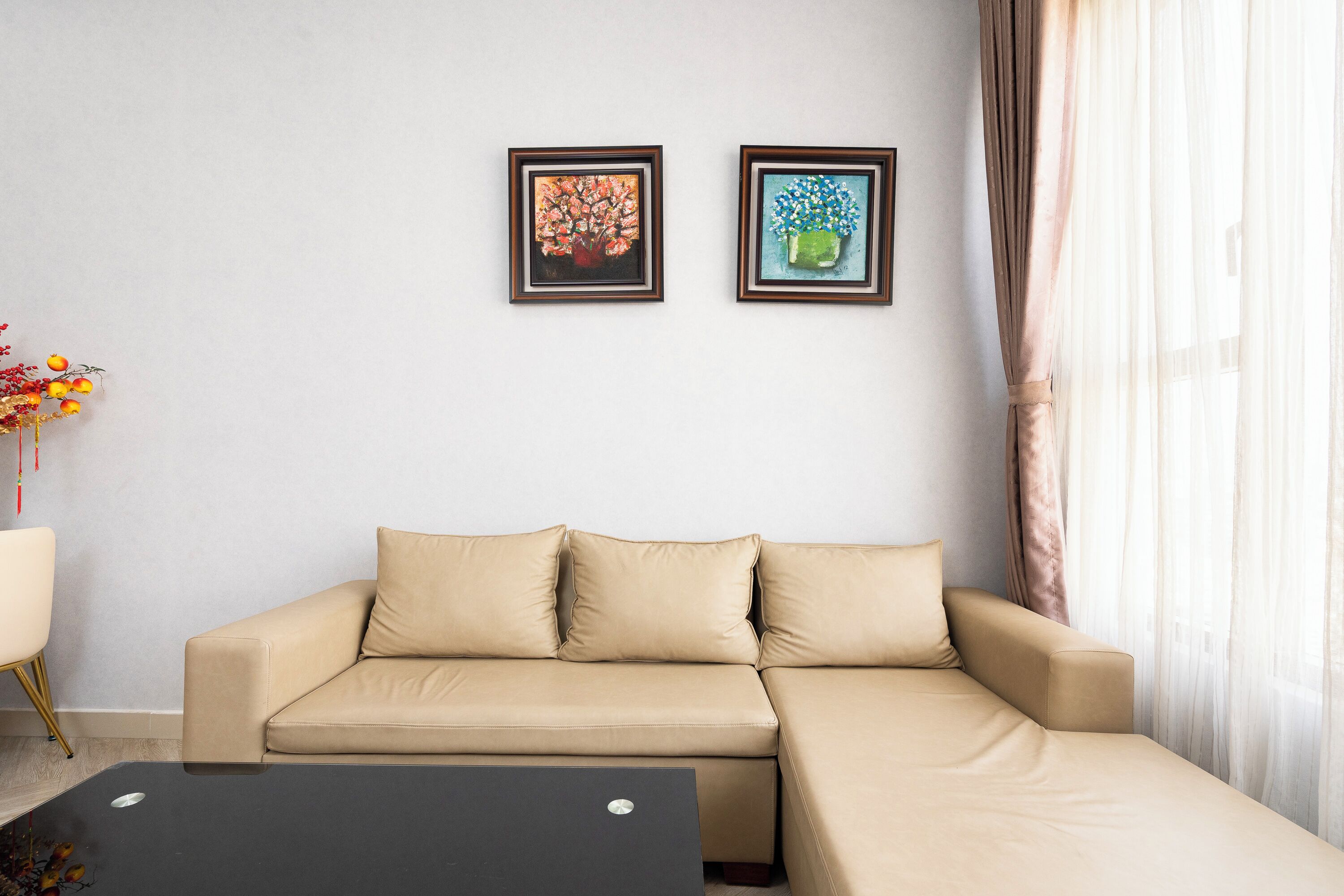 A beige sofa with a black coffee table in a room with two framed artworks on the wall.