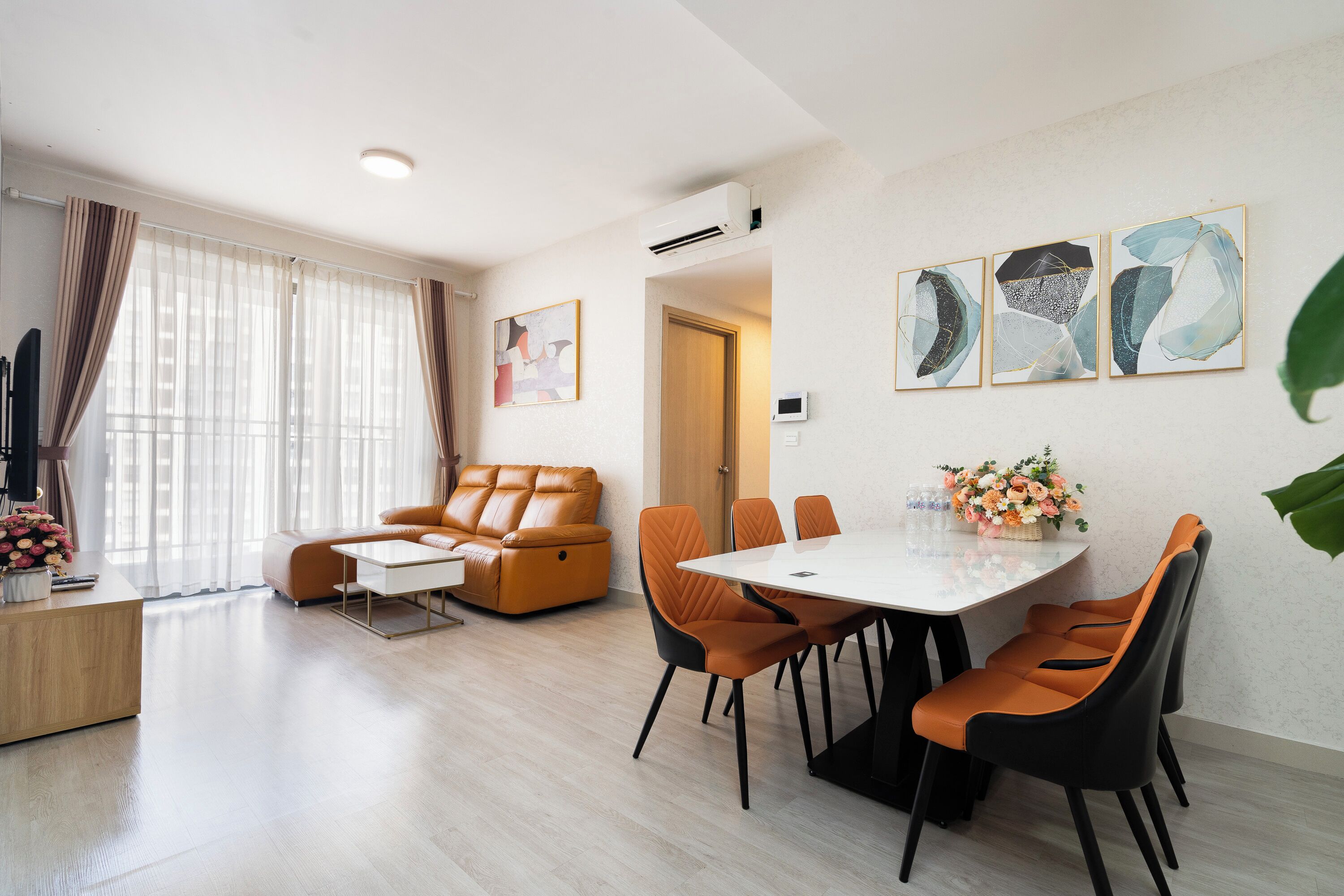 A modern living room with a sofa, a coffee table, and a dining area with chairs and a table.