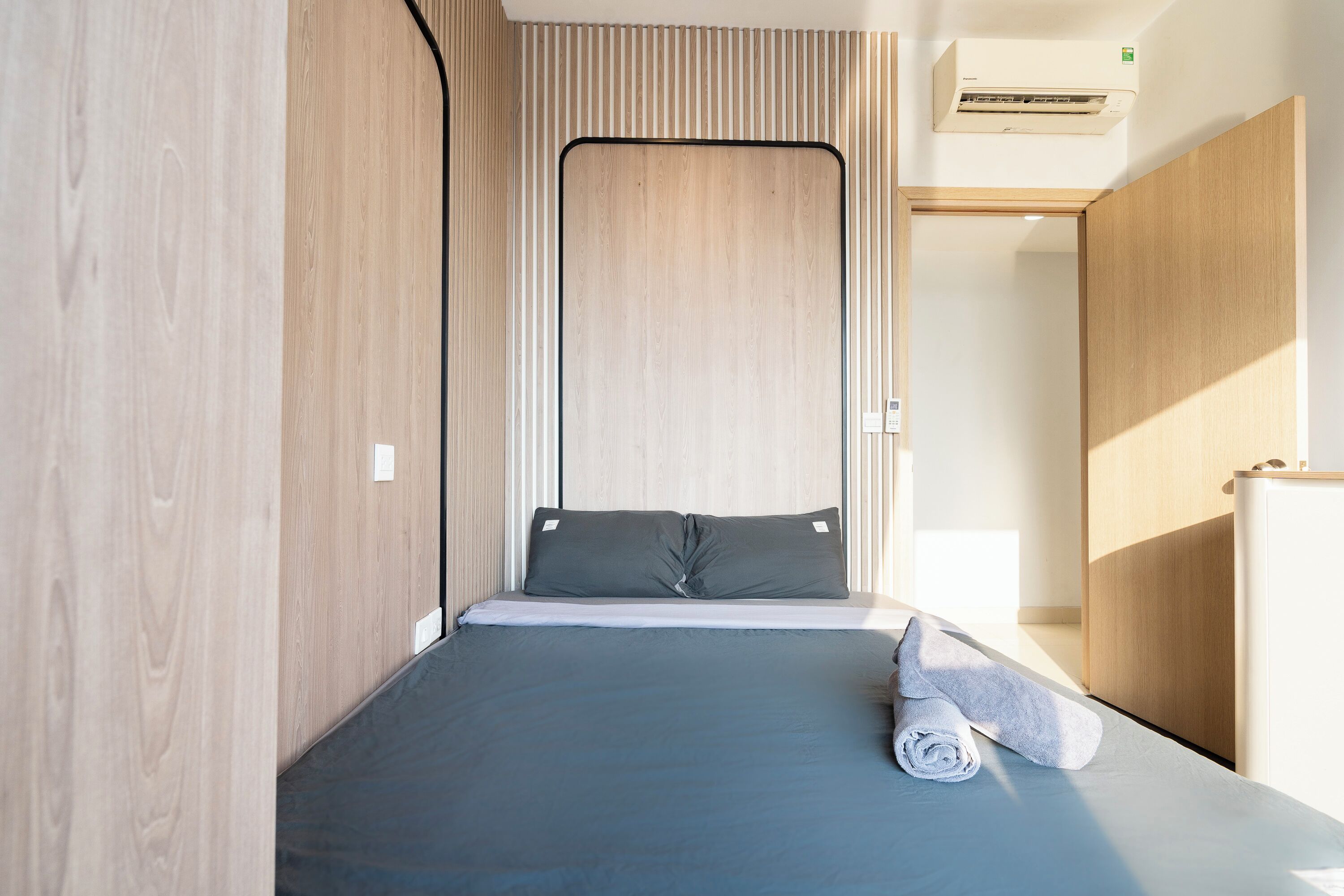 Una camera da letto moderna con un letto, un asciugamano arrotolato e un'armadio in legno.