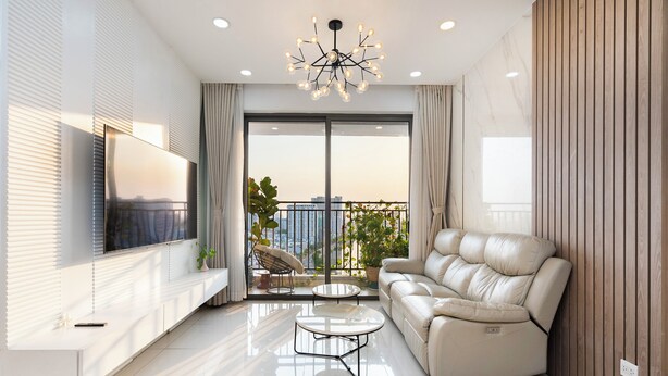 Ein modernes Wohnzimmer mit einer Couch, einem Fernseher und einem Balkon mit Pflanzen.