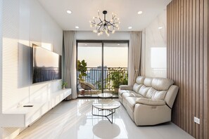 A modern living room with a sofa, TV, and a balcony with plants. - Annie  Apartment - Rivergate Resident  (Ho Chi Minh City)