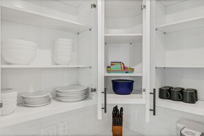 A kitchen with white cabinets, a blue pot, and black mugs on the shelves.