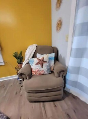 Relax in a cozy corner with a comfortable armchair, decorative pillow, and a potted plant.