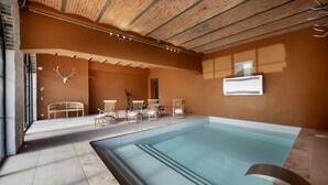 Área de piscina com teto de madeira, um banco e cadeiras.