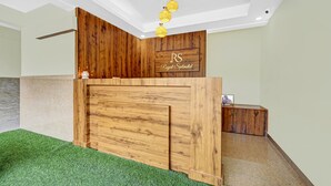 Una recepción con detalles de madera, un letrero que dice "RS Royal Splendid" y un mueble pequeño a la derecha.