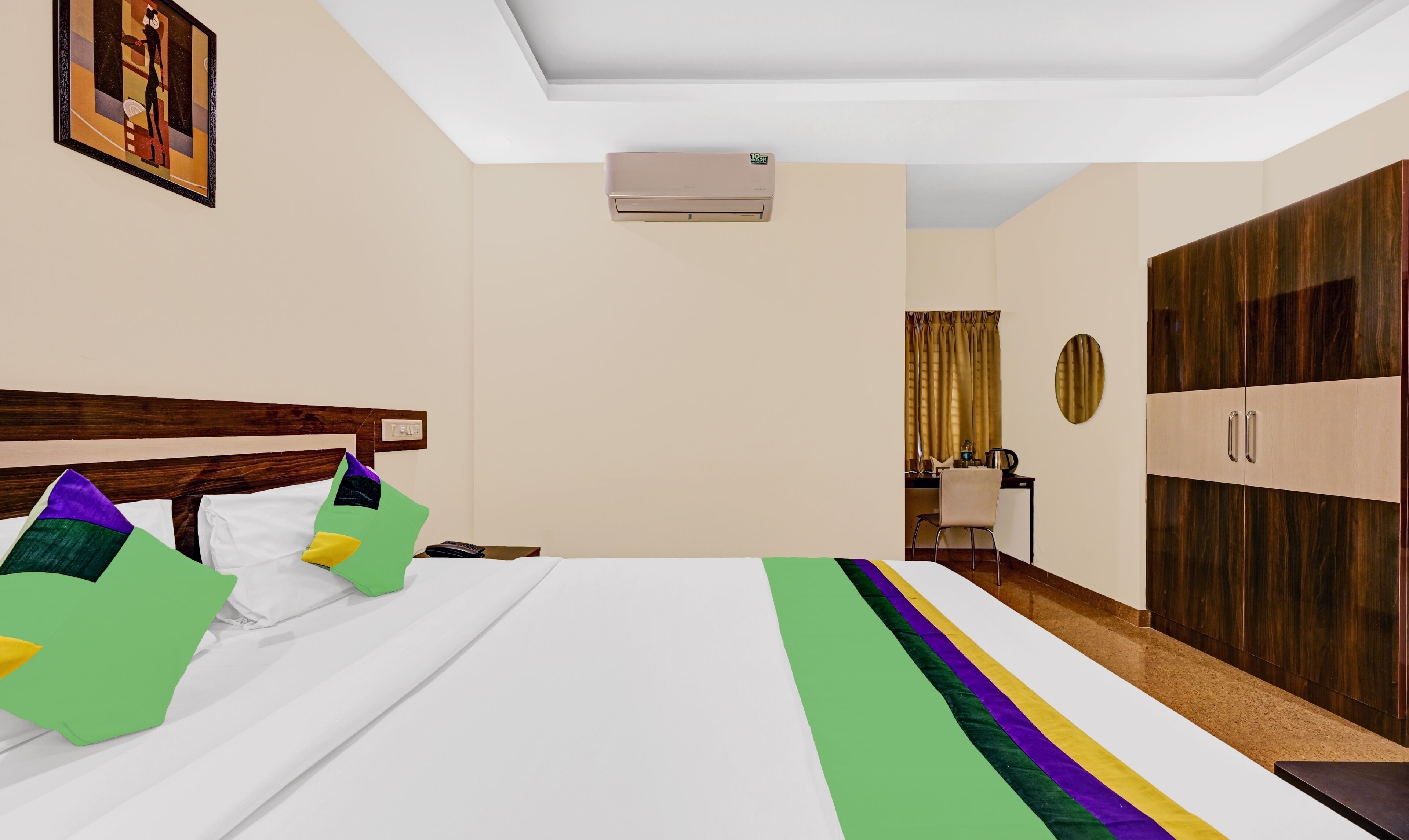 Habitación de hotel con cama, escritorio, armario y unidad de aire acondicionado.