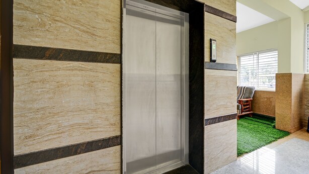 Un pasillo con pared de mármol, una puerta y un ventanal con persianas.