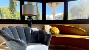 A room with a blue armchair, a yellow sofa, and a lamp. - Domaine de la Reynaude (Aurons)