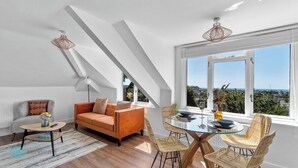 A modern living room with a sofa, a glass table, and a view of the city. - The Penthouse By Pureserviced (Plymouth)