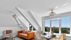 A modern living room with a sofa, a glass table, and a view of the city. - The Penthouse By Pureserviced (Plymouth)
