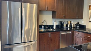 Una cucina moderna con elettrodomestici in acciaio inossidabile, mobili in legno e un piano di lavoro nero.