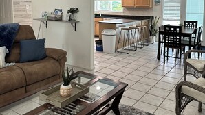 A spacious living area with a sofa, coffee table, and dining area with chairs and a table. - Ellie’s Landing 1 – Chill & Grill Dockside Oasis (Port Charlotte)