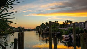 A waterfront property with docked boats, wooden posts, and palm trees. - Ellie’s Landing 1 – Chill & Grill Dockside Oasis (Port Charlotte)