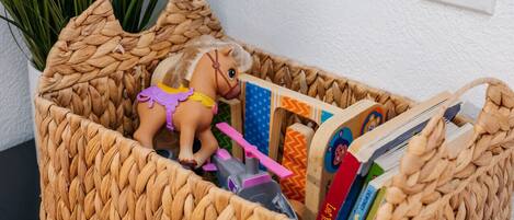 A woven basket containing a toy horse, books, and a toy car.