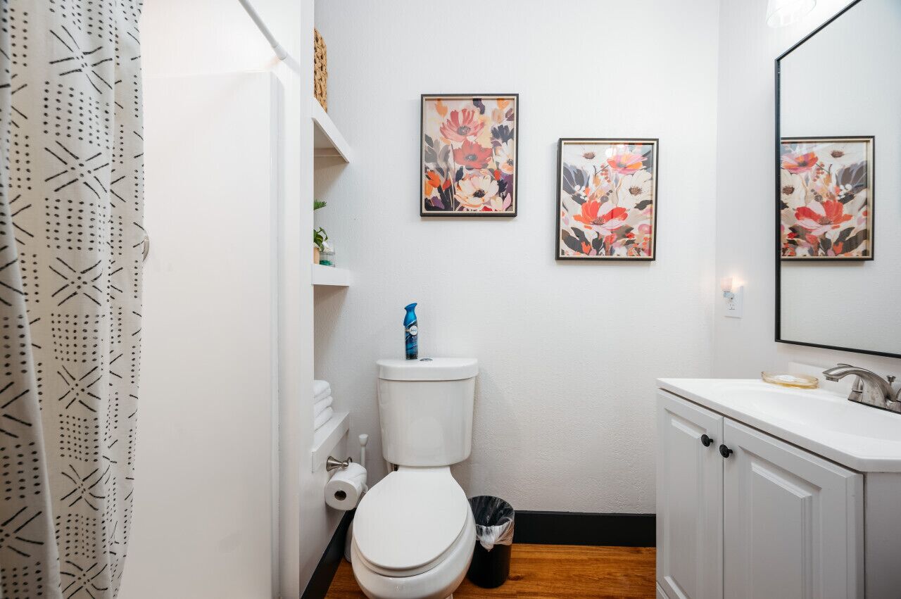 A bathroom with a toilet, sink, and two framed floral artworks on the wall.
