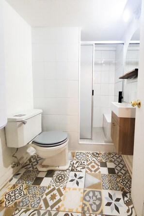 A bathroom with a toilet, a shower, and a sink.